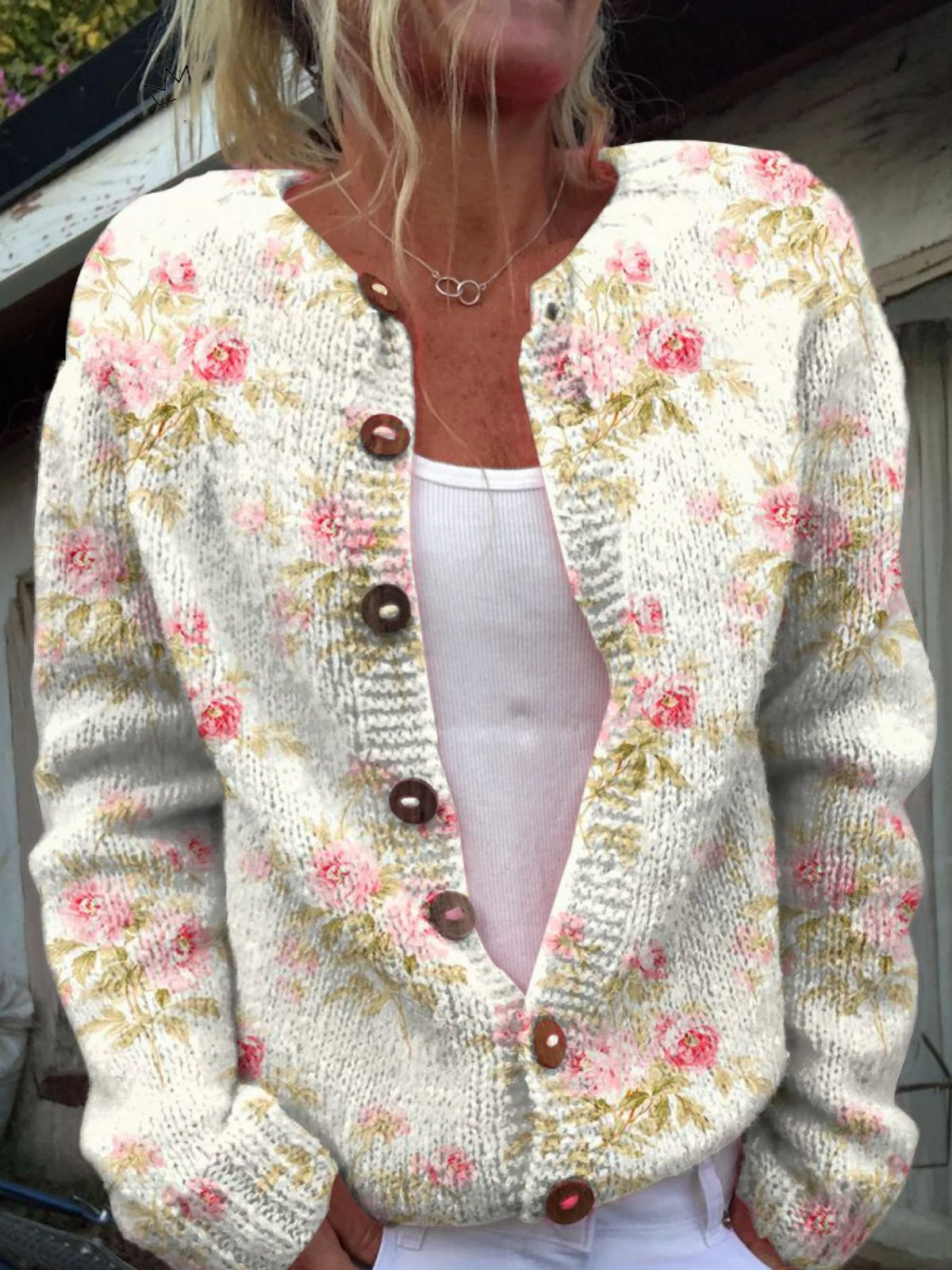 Elegant strikket ullgenser med friske rosa blomster og grønne blader samt knapper for en sofistikert og frisk stil